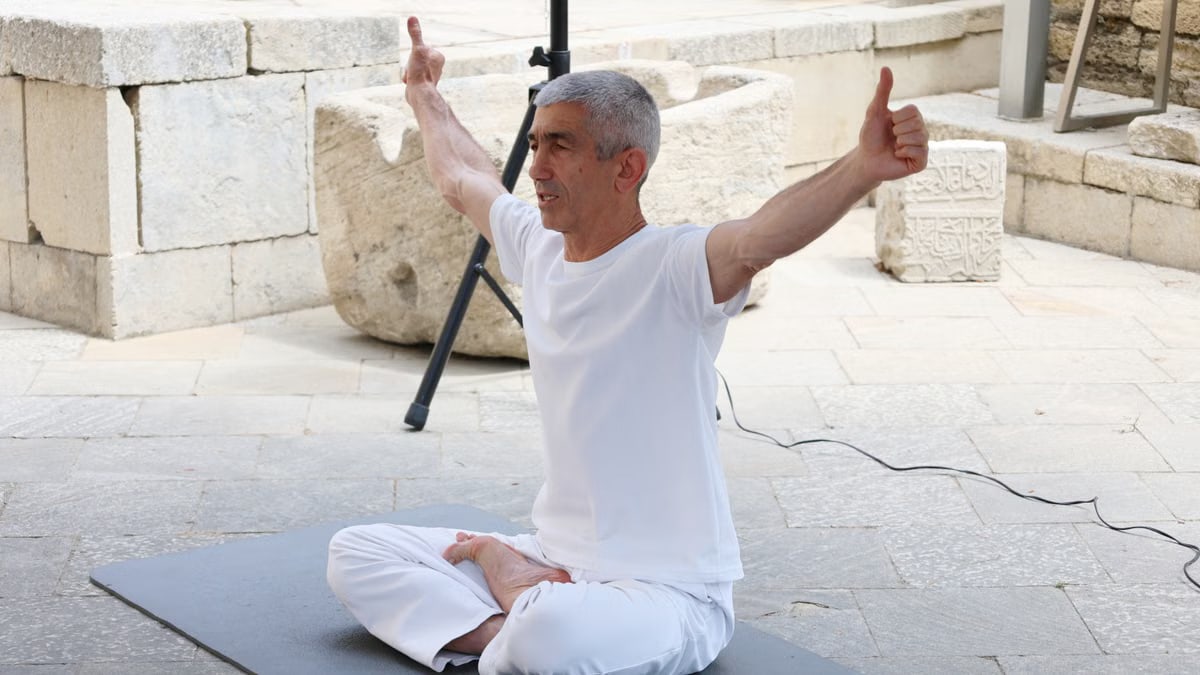 A senior man meditating in a yoga pose outdoors, expressing tranquility and balance.